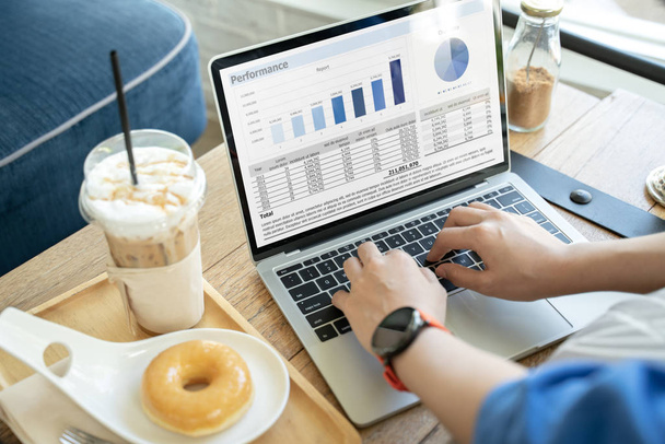 Ręce kobiet korzystających z laptopa z wykresami biznesowymi siedząc obok kawy i pączka.Raport finansowy z wykresem ciasta i dane na laptopie z rękami kobiety biznesu w kawiarni. - Zdjęcie, obraz
