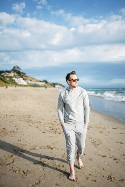 A guy in sunglasses walks along the coastline - Foto, Imagen
