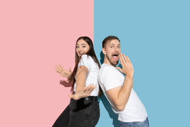 Jonge emotionele man en vrouw op roze en blauwe achtergrond - Foto, afbeelding