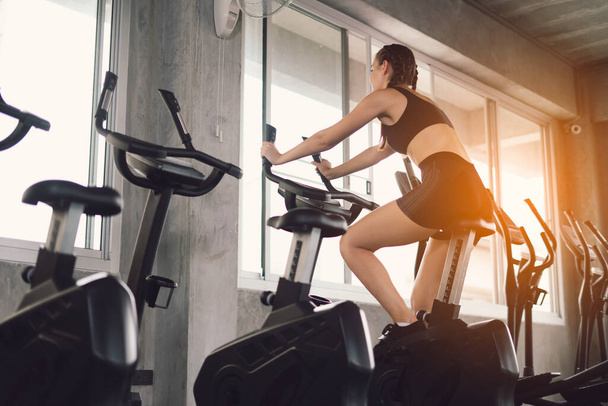 Young People - group of women and men - doing sport biking in the gym for fitness. Young woman workout in gym healthy lifestyle. Change for health concept. - Foto, Imagen