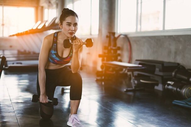 Young athletic woman working out with dumbbells in fitness club - Foto, Imagem