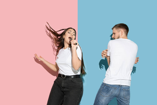 Young emotional man and woman on pink and blue background - Foto, Bild