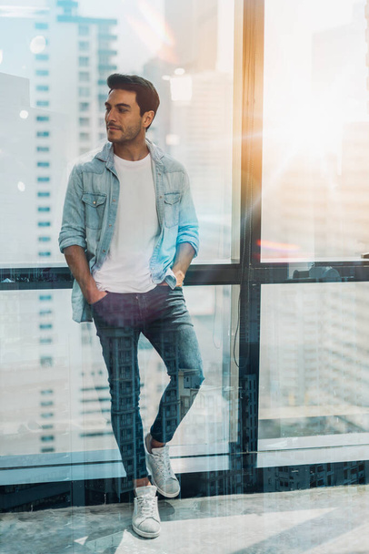 Portrait of relaxed businessman in modern office.Business young man relax after work of office window with business district view. - Photo, image