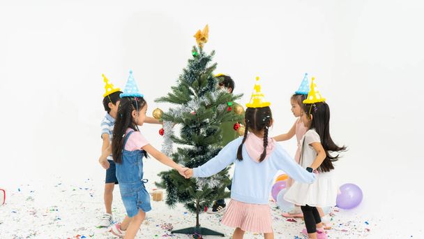 Happy kids throwing colorful confetti in a room.Group of kids celebrate birthday party together.Group of children in Christmas hat with presents.Group of children decorating Christmas tree. - Fotografie, Obrázek