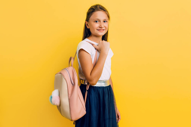 Portrait of a smiling little schoolgirl with a backpack on a yel - Fotoğraf, Görsel