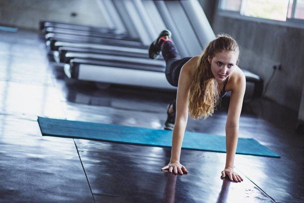 Woman at the gym doing stretching exercises and smiling on the floor.Sport background. - Foto, Imagem
