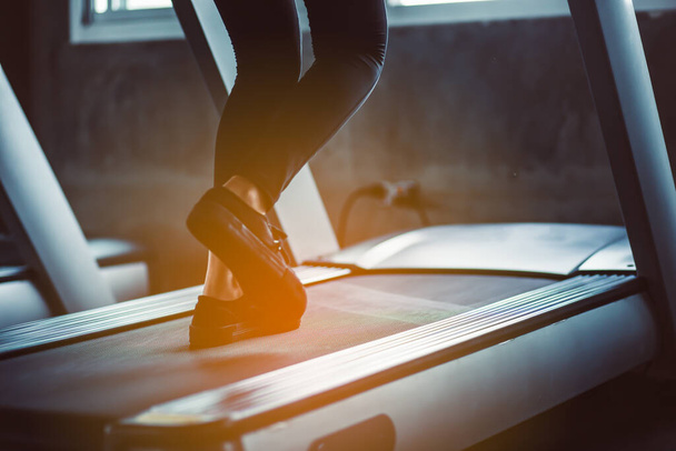 Female muscular feet in sneakers running on the treadmill at the gym. Concept for fitness, exercising and healthy lifestyle.sport concept. Young sporty woman stretching at gym. Change for health concept.Fitness woman in training showing exercises wit - 写真・画像