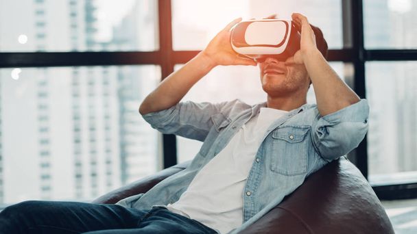 Bearded man wearing virtual reality goggles in modern office. Smartphone using with VR headset.Young businessmen wearing VR glasses play games at work time.Horizontal, blurred. - Foto, Imagem