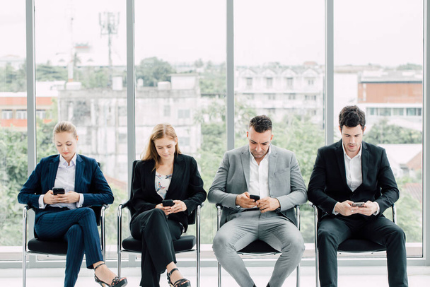 Group of business people sitting chair and using their mobile phones, ignoring work and social networking. - Photo, image