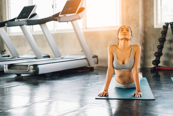 Fit girl relaxing in gym, performing yoga pose in class at sunset - Photo, Image