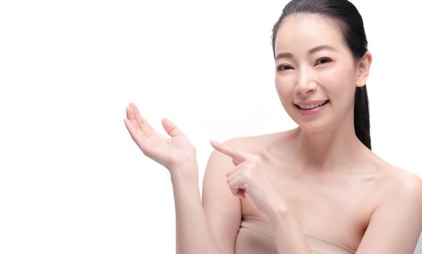 Tender Asian woman with natural makeup pointing on hand, presenting with copy space  - Valokuva, kuva