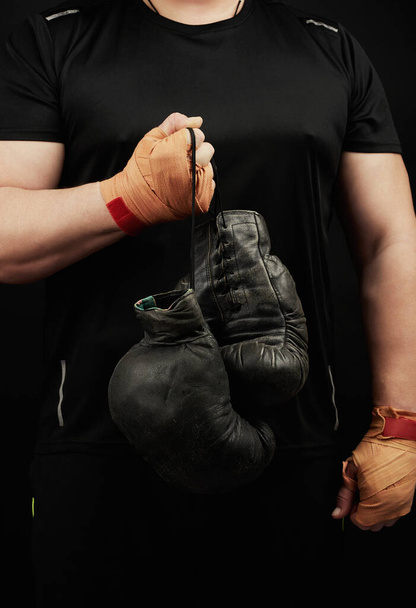 atleta muscular en un uniforme negro sostiene muy viejo boxeo negro
  - Foto, Imagen