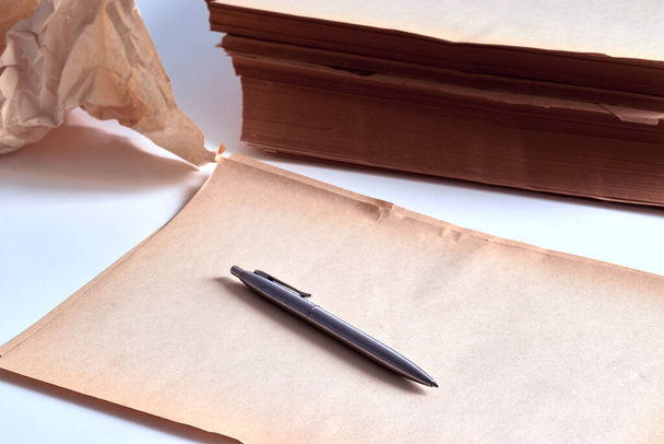 une pile de vieux papiers sur une surface blanche avec un stylo
 - Photo, image