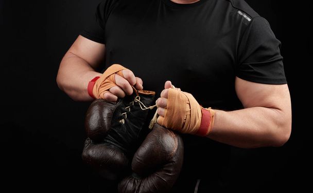 athlète musclé en uniforme noir tient très vieille boxe brune
  - Photo, image