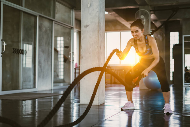 Young Asian girl training with battle ropes in cross fit gym - Photo, image
