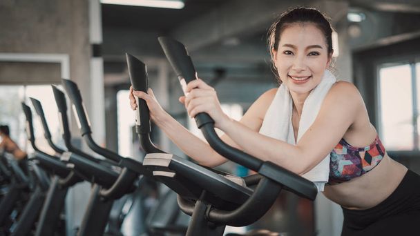 Young Asian woman exercising on bicycle in fitness center. - Fotografie, Obrázek