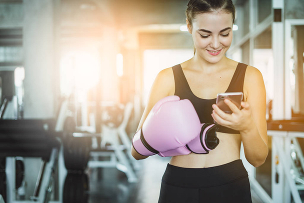 woman using mobile phone and listen music at gym.Healthy concept, Beautiful sports girl relax after workout in gym. - Foto, Imagem