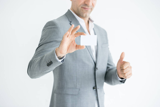 young businessman holding business card and showing thumbs up gesture.Close up of a businessman hand holding a business card isolated on a white background. - Foto, Bild