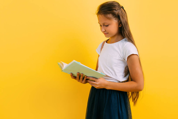 Adolescente leyendo un libro sobre un fondo amarillo
 - Foto, imagen