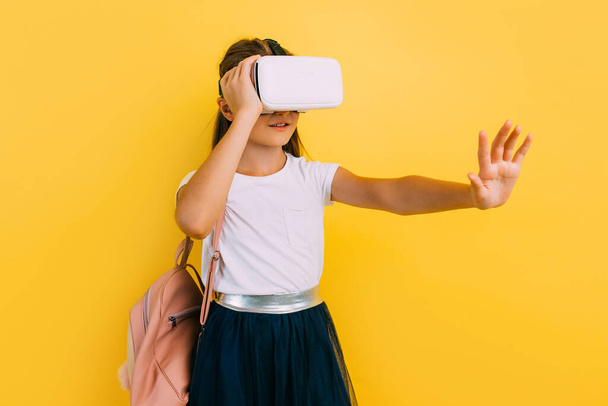 Little girl in school uniform with virtual reality glasses - Фото, изображение