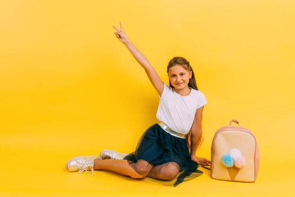 School girl in school clothes on a yellow background - Valokuva, kuva