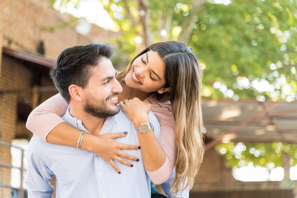 Happy Hispanic boyfriend piggybacking girlfriend during date - Photo, Image