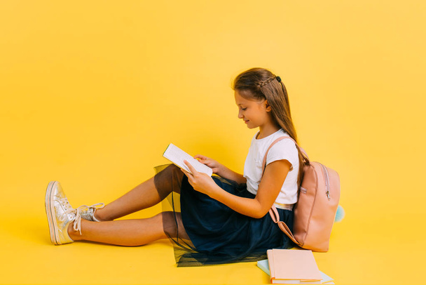 Smart teenage girl in school clothes doing homework reading a book - Foto, Imagem