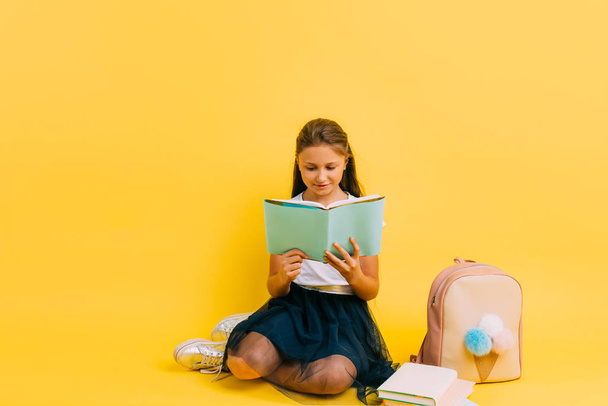 Chytrý dospívající dívka ve škole oblečení dělá domácí úkol čtení knihy - Fotografie, Obrázek