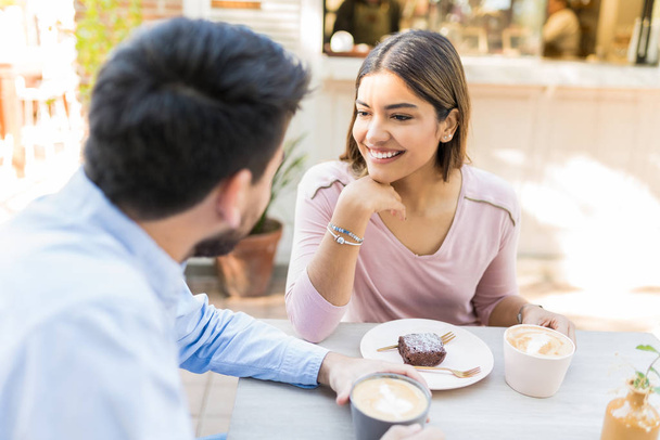 Χαμογελαστή νεαρή γυναίκα απολαμβάνοντας καφέ με το φίλο της στο καφέ - Φωτογραφία, εικόνα
