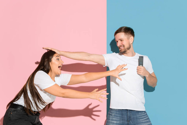 Young emotional man and woman on pink and blue background - Φωτογραφία, εικόνα