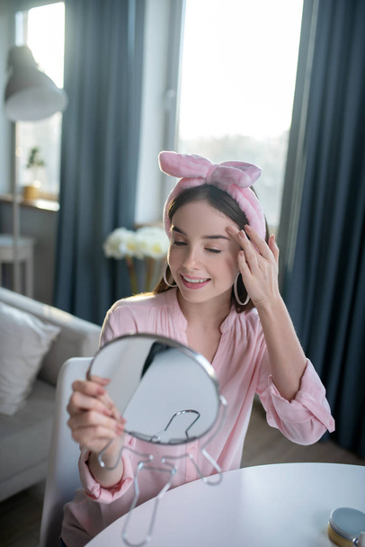 Smiling pretty girl in a pink headband looking at herself - Фото, зображення