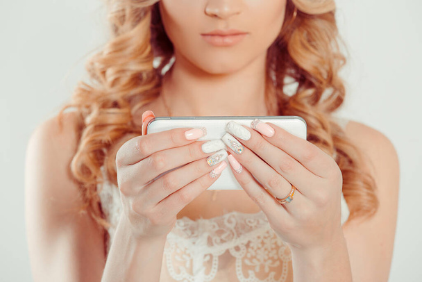 Trendy with phone. Nail Polish. Art Manicure. Modern style pink white Nail Polish. Beauty hands holding mobile cellphone. Stylish pastel Color classic bride Nails design isolated white background wall - Φωτογραφία, εικόνα