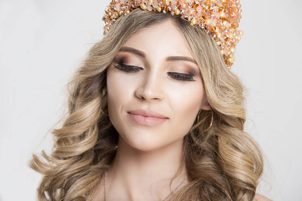 Beautiful blonde girl in a golden crown on grey background, eyes closed - Valokuva, kuva