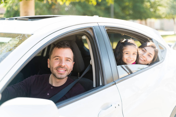 Sonrientes padres sentados con su hija en el coche en el día soleado
 - Foto, imagen