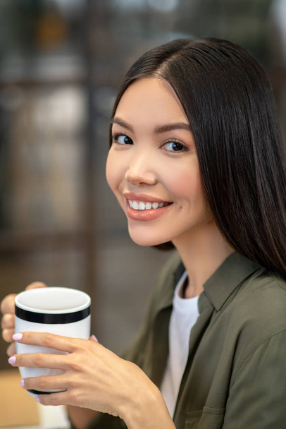 Long-haired brunette asian girl sitting and having coffee - Foto, Imagem