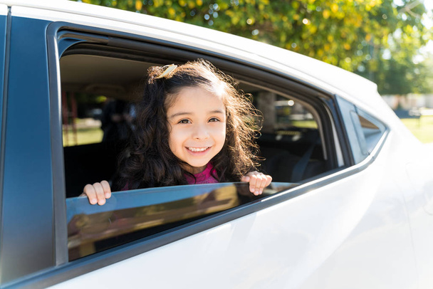 Portrait Of Cute Girl Leaning On Car Window During Sunny Day - Foto, imagen