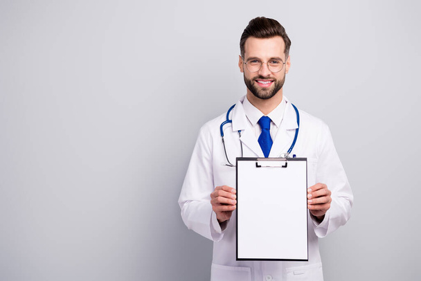 Portrait of nice attractive cheerful cheery bearded doc showing paper document agreement service terms insurance medicare first aid help assistance isolated on light white gray pastel color background - Valokuva, kuva