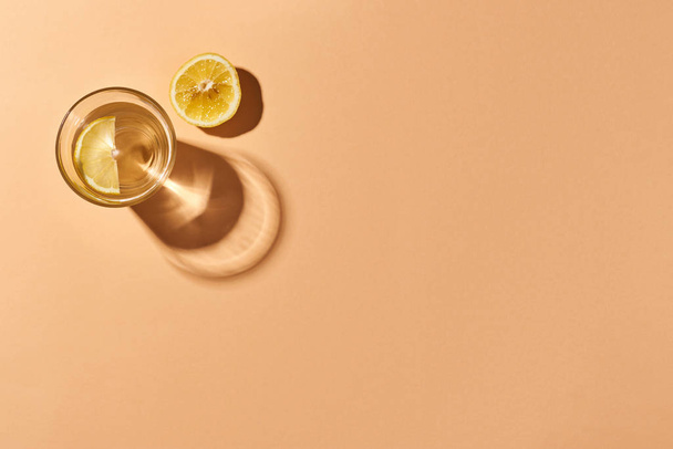 Un vaso de agua con limón y una rodaja de limón aislada sobre naranja. Fondo naranja. Vista superior
. - Foto, Imagen