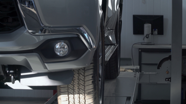 A hidraulikus platform cserbenhagy egy autót az autószerelő műhelyben. Gépjármű-szolgáltatás - Felvétel, videó