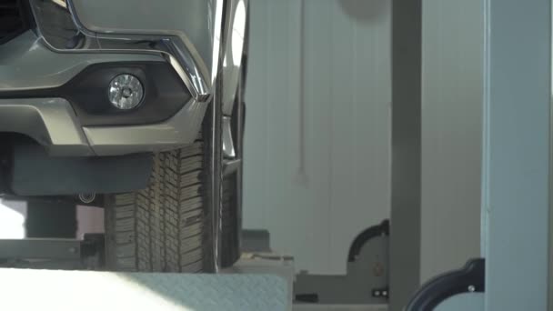 A hidraulikus platform cserbenhagy egy autót az autószerelő műhelyben. Gépjármű-szolgáltatás - Felvétel, videó