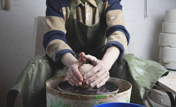 陶器製の車輪の上の陶芸家の手を閉じる。古い伝統的な芸術、手作り、粘土やセラミックの生産。やわらかい光の中で陶芸体験 - 写真・画像