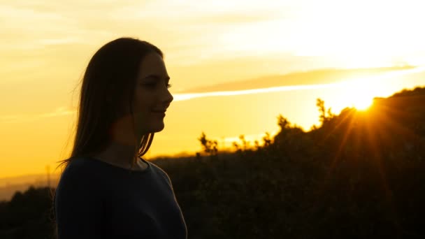 Sylwetka kobiety oddychającej świeżym powietrzem o zachodzie słońca w górach - Materiał filmowy, wideo