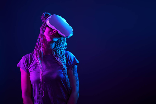 La femme utilise un casque de réalité virtuelle. Portrait studio lumière néon. - Photo, image
