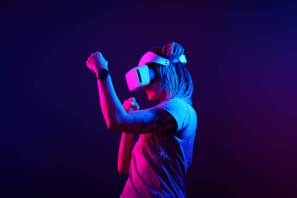 Woman is using virtual reality headset. Neon light studio portrait. - Photo, image