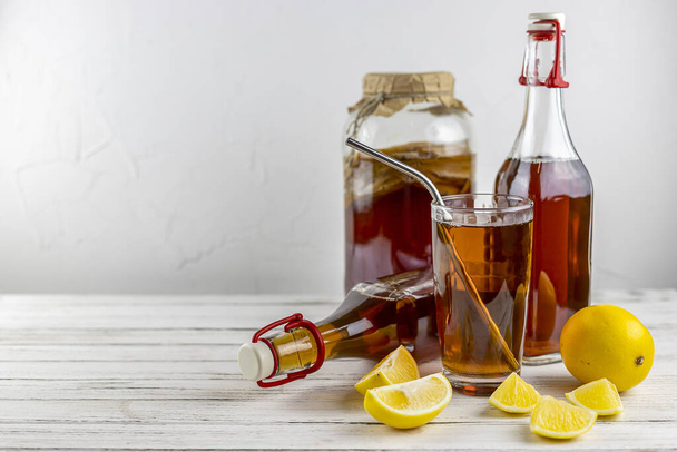 Суперпродукт Kombucha про біотичний чайний гриб напій у скляній пляшці та банці з лимоном на білому тлі
 - Фото, зображення