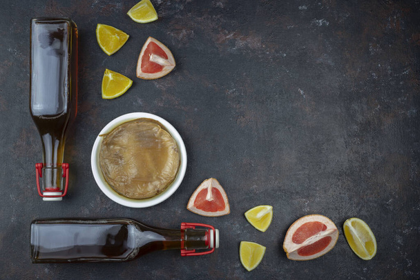 Kombucha superalimento pro biótico té hongo bebida en botella de vidrio con naranja, pomelo sobre fondo oscuro
. - Foto, imagen