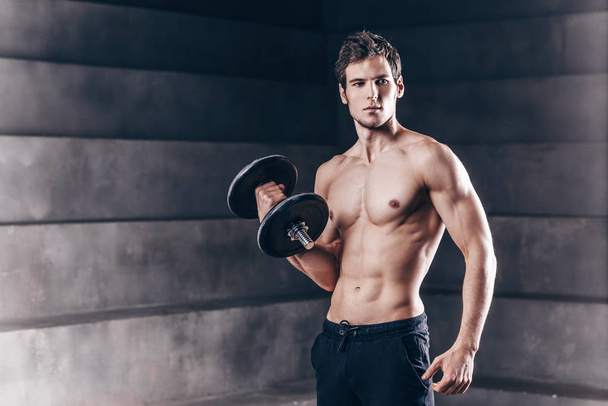 Strong handsome man with dumbbells.  - Фото, изображение