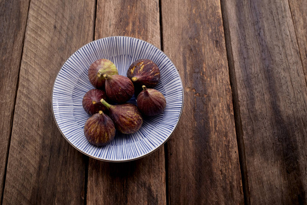 figs on plate on wooden table background - Fotoğraf, Görsel