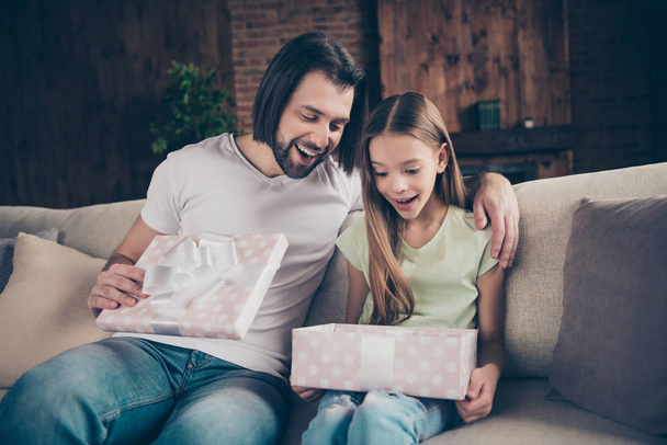 Photo of little adorable funny shocked lady her handsome daddy sit cozy sofa giving receiving open big giftbox unexpected birthday present celebrate domestic atmosphere indoors - Фото, изображение