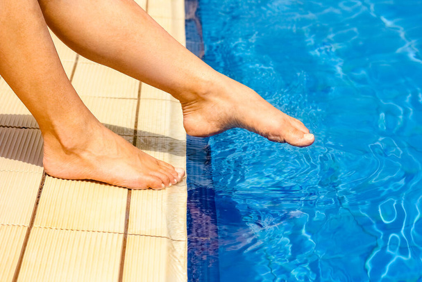 beautiful legs of a girl near a swimming pool on the sea backgro - Фото, изображение